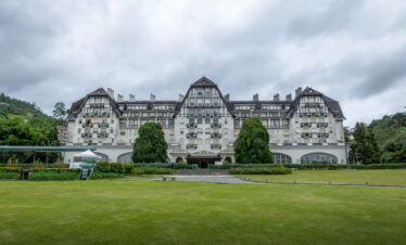 Front view of the Quitandinha Palace in Petrópolis, Rio de Janeiro, Brazil, a historic landmark of the Imperial City surrounded by green hills.